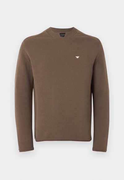 Καφέ πλεκτό πουλόβερ με μακριά μανίκια, στρογγυλή λαιμόκοψη και μικρό λευκό λογότυπο στο αριστερό στήθος, σε απλό φόντο.