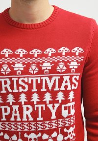 Roter Strickpullover mit weißen Weihnachtsmotiven, darunter Pilze, Bäume und der Text "WEIHNACHTSFEIER", mit einem gerippten Halsausschnitt.