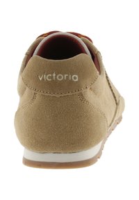 Zapatilla de ante beige con un collar acolchado, una entresuela blanca y una suela de goma texturizada. Logo "victoria" en blanco en el talón.