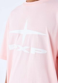 Camiseta de algodón rosa con un gran gráfico de una estrella blanca y el texto "PXP". Manga corta y cuello redondo con una textura suave.