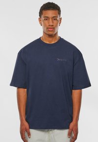 Marineblå oversized t-shirt i bomuldsstof, med korte ærmer og en lille "Dropsize" brodering på brystet.