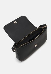 Sort læder crossbody taske med lynlåslukning og trykknap. Glat tekstur med hardware i guld. Indvendigt er der ét rum.