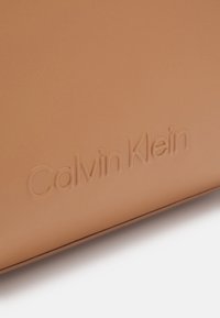 Väri nahkalompakko, jossa on kohokuvioitu "Calvin Klein" -logo. Sileä pinta, puhtaat linjat ja minimalistinen muotoilu. Ei näkyvää metalliosaa tai koristeita.