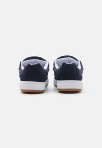 Námořnické modré tenisky se svrškem z sueden a síťoviny, bílým jazykem a gumovou podešví. Disponují texturovanou zadní částí a hladkými bočními panely.