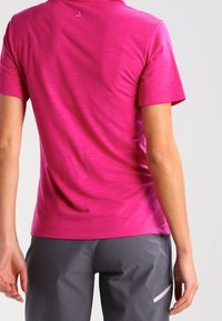 Chemise ajustée à manches courtes de couleur rose vif, avec un motif texturé, un col rond et un tissu lisse à éclat subtil.
