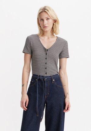 Bodysuit à rayures noir et blanc à manches courtes avec un col en V et une fermeture à boutons, associé à un pantalon large taille haute en denim foncé.