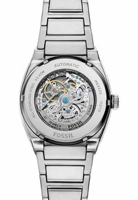 Automatische Uhr aus Edelstahl mit transparentem Gehäuseboden, der komplizierte Zahnräder zeigt, blauen und goldenen Akzenten sowie einem gebürsteten Silberarmband.