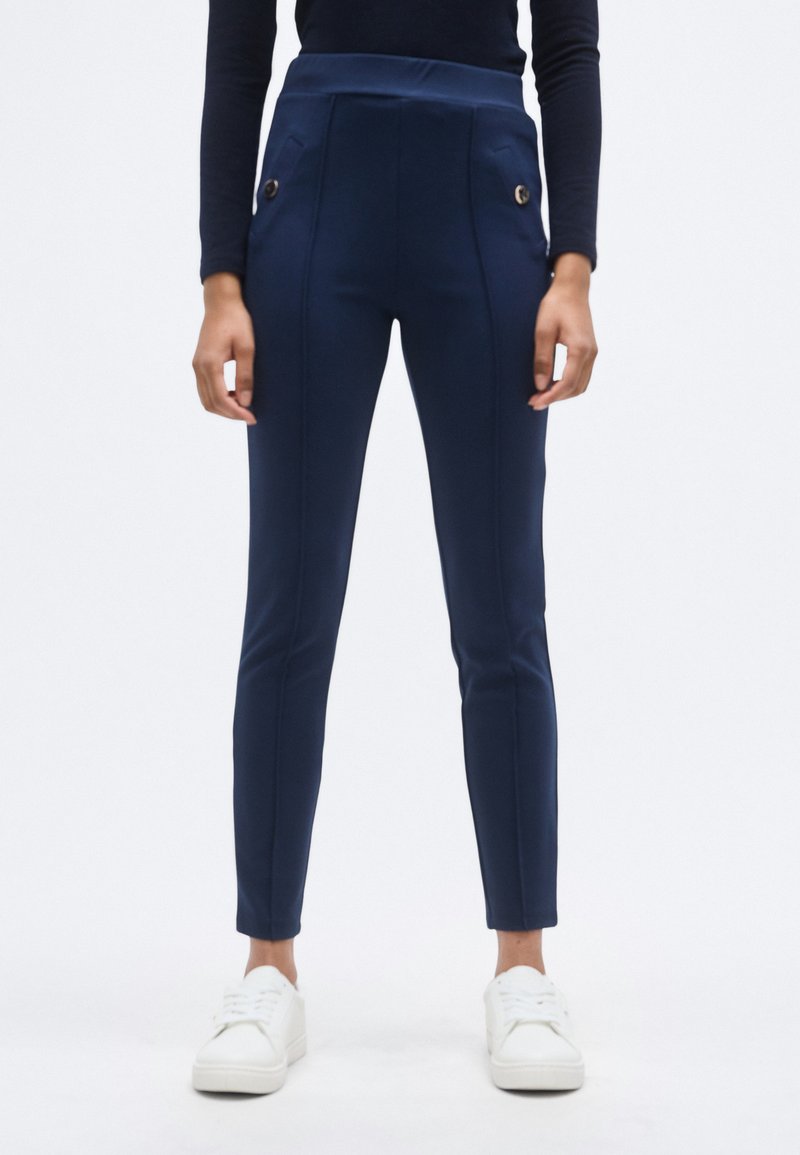 Σκούρο μπλε παντελόνι ψηλόμεσο από ελαστικό ύφασμα, με δύο μπροστινές τσέπες διακοσμημένες με μεταλλικά κουμπιά και λεπτή γραμμή εφαρμογής.