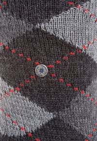 Strickwollschal in Dunkelgrau, Hellgrau und Rot. Mit einem Diamantmuster und einem metallischen Logo-Akzent an der Seite. Weiche Textur.