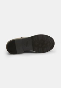 Suola di scarpa nera con gomma testurizzata per aderenza, caratterizzata da una forma liscia e curva e un marchio inciso sul lato.