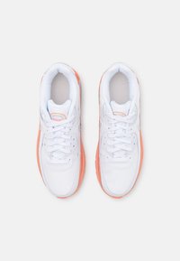 Vita sportskor med orange detaljer, med ett slätt läderöverdrag, snörning, vadderad krage och texturerad gummi sula.