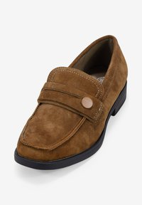 Mocasines de ante marrón con puntera redondeada, que presentan dos correas horizontales en el empeine y un pequeño botón de acento redondo. Suela de goma negra.