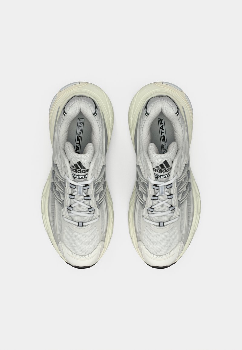 Scarpe sportive grigie con una tomaia testurizzata, suola intermedia spessa bianca e accenti neri sulla linguetta e sul lato. Presentano lacci e un colletto imbottito.