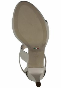 Sandalo bianco con tacco alto caratterizzato da una finitura liscia e lucida, cinghie eleganti e punta affusolata. Include un piccolo tacco a blocco e un accento metallico.