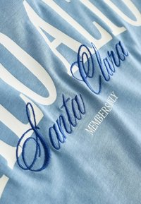 Vaaleansininen kangas, jossa valkoista ja tummansinistä tekstiä "Santa Clara" ja "MEMBERS ONLY" kirjailuna.