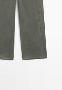 Pantalon gris à jambes larges montrant un ourlet droit et une couture latérale visible sur fond blanc.
