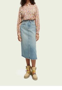 Halenka s květinovým vzorem a dlouhým rukávem v růžové barvě, doplněná světle modrou denimovou sukní. Béžové boty s barevnými tkaničkami a kožešinovým lemem.