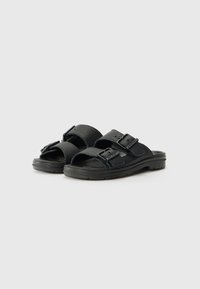 Svarta sandaler med breda remmar som har justerbara spännen. Ovandelen har en strukturerad yta, med en vadderad sula och minimalistisk design.