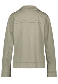 Jasnooliwkowa kurtka wykonana z trwałej tkaniny, z charakterystycznym szpiczastym kołnierzem, długimi rękawami i prostymi zdobieniami szwów. Przedstawiony widok od tyłu.