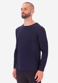 Camicia a maniche lunghe blu navy con scollatura rotonda, realizzata in tessuto morbido, con una texture liscia e un orlo dritto.