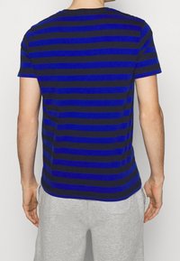 Blau- und schwarz gestreites T-Shirt mit kurzen Ärmeln, Rundhals und einer glatten Textur, von hinten präsentiert. Graue Shorts sind sichtbar.