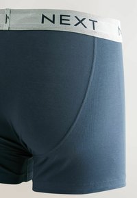 Háromszoros sötétkék férfi boxer alsónadrág, fehér elasztikus derekú, "NEXT" márkájú, a jobb hátsó oldalról mutatva.