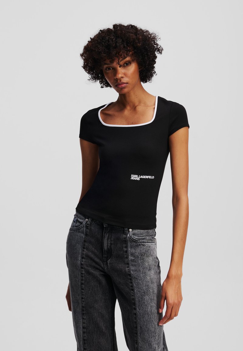 Juodas trumpomis rankovėmis viršus su kvadratiniu iškirpimu ir balta apdaila; priekyje yra "Karl Lagerfeld Jeans" logotipas.