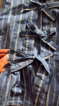 Tessuto a righe blu navy con linee bianche, caratterizzato da molteplici cravatte. La texture è leggermente stropicciata, mettendo in evidenza il materiale simile al cotone.