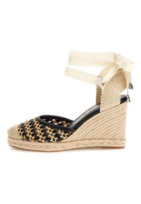 Sandalo wedge in tessuto intrecciato nero con dettagli dorati, suola in juta beige e lacci alla caviglia. Caratterizzato da punta aperta e design laterale testurizzato.