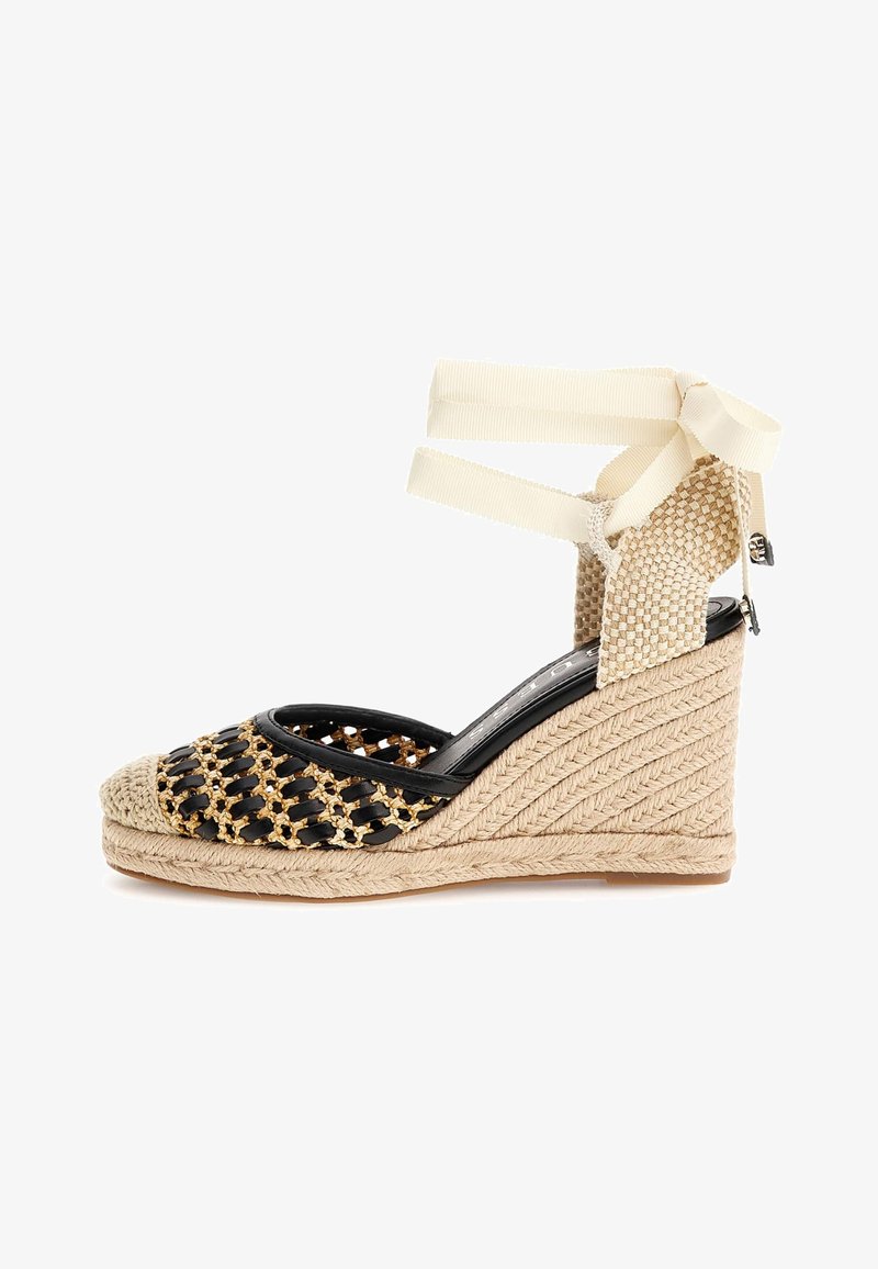 Černé tkané sandály na klínovém podpatku se zlatými akcenty, béžovou jutovou podrážkou a vázáním kolem kotníku. Mají otevřenou špičku a strukturální design na boční straně.