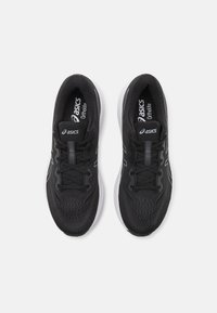 Scarpe atletiche nere con tomaia in rete traspirante, suola bianca e dettagli riflettenti. Dotate di una soletta ammortizzata e lacci piatti.