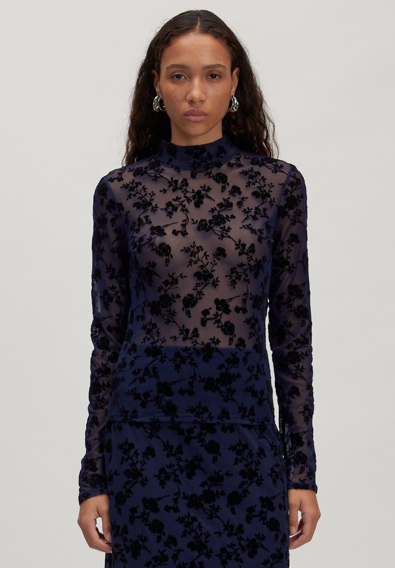 Langärmlige, figurbetonte Bluse in Marineblau aus transparenter Stoff mit schwarzer Floralstickerei; hohes Kragen-Design mit zarten, strukturierten Akzenten.
