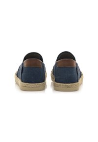 Scarpe slip-on in tela blu navy con dettagli in pelle marrone e suole in juta intrecciata, caratterizzate da una punta arrotondata e da un design minimalista.
