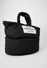 Czarna, puszysta torba na ramię o zaokrąglonym kształcie, z górnym uchwytem i białą metką z napisem "MADS NØRGAARD COPENHAGEN".