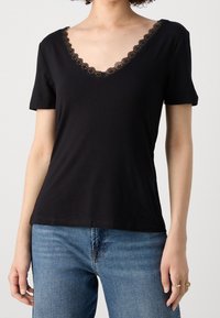 T-shirt nera a maniche corte con scollatura a V, caratterizzata da un bordo in pizzo. Realizzata in tessuto morbido, con una forma aderente e una texture liscia.