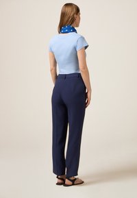 T-shirt fitted bleu clair associ�é à un pantalon noir marine sur mesure et une écharpe bleu à motifs, avec des manches courtes et un design simple.
