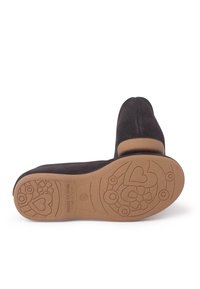 Zapatilla de ante negra con punta redondeada, que cuenta con una suela de goma grabada con patrones florales y de corazones. Textura suave y tacón bajo.