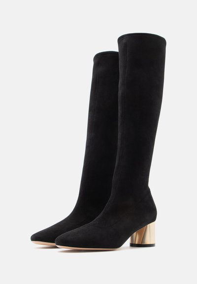 Botas pretas de camurça acima do joelho com biqueira apontada e salto bloco dourado. Apresentam um design elegante e textura suave com detalhes de costura.