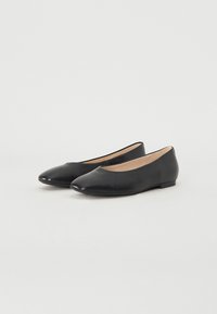 Ballerines noires en cuir avec un bout pointu, un talon plat et un design minimaliste. Texture lisse et détails de couture simples.