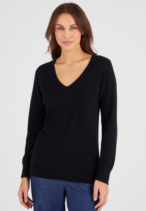 Zwarte V-hals trui van zachte stof, met lange mouwen en een licht getailleerd silhouet, in combinatie met donkerblauwe broek.