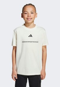 Weißes Baumwoll-T-Shirt mit einem schwarzen Adidas-Logo und dem Text "ADIDAS SPORTSWEAR" in Fettdruck. Runder Ausschnitt und kurze Ärmel.