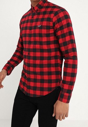 Rood en zwart geruit flanellen overhemd met een button-down kraag, lange mouwen en een logo-accent op de linkerborst. Iets gebogen zoom.