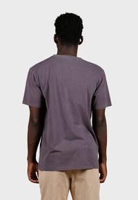 Tričko s krátkym rukávom a okrúhlym výstrihom v tmavej purpurovej farbe, vyrobené z bavlny. Viditeľný šev a štítok v oblasti zadného výstrihu.