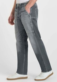 Pantaloni in denim grigio con una vestibilità rilassata, sfumature più chiare e più scure a contrasto, cinque tasche e dettagli di cucitura discreti.