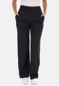 Pantaloni neri a gamba larga con cintura elastica, tasche laterali e dettagli dorati sull'orlo. Realizzati in tessuto morbido e liscio.
