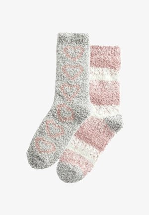 Chaussettes douces en gris avec des motifs de cœurs roses sur l'une, et des rayures roses et blanches sur l'autre. Texture douce et design léger.