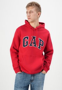 Rode hoodie van een katoenmix, met een voorzak en een groot navy "GAP" logo. Hij heeft een capuchon met trekkoorden en ribgebreide manchet.