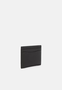Black leather cardholder with a textured surface, featuring four slots and white stitching along the edges. Compact rectangular shape.