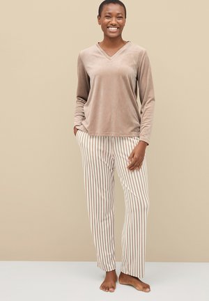 Beige fluwelen blouse met lange mouwen en een V-hals, gecombineerd met crèmekleurige en lichtbruine gestreepte broek. Zachte textuur, relaxte pasvorm.