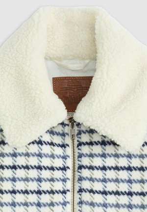Fleece gevoerde jas met een wit en marineblauw houndstooth patroon, voorzien van een crèmekleurige kraag en een bruin leren label. Rits aan de voorkant.